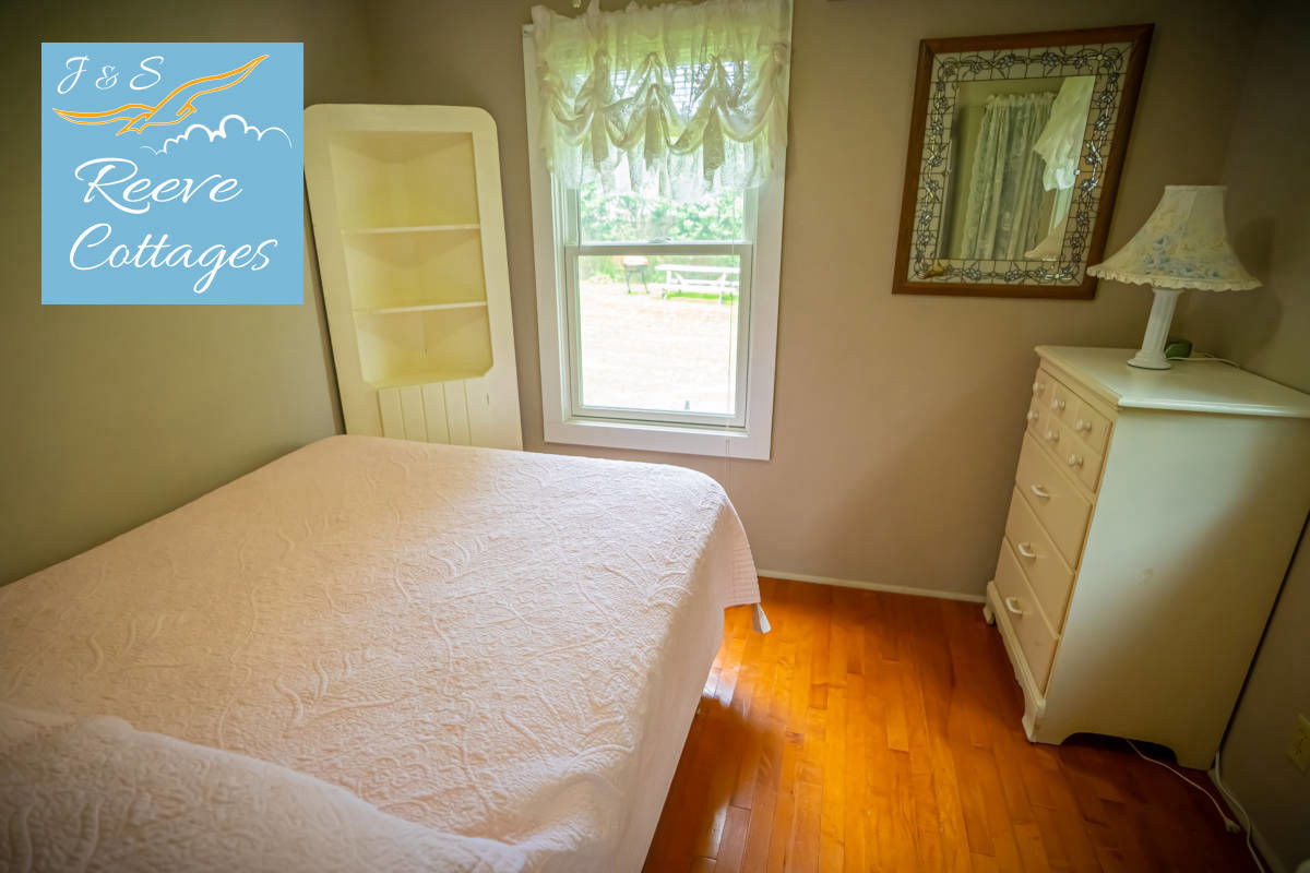 Cozy Waterfront Cottage 4 shows bedroom one with queen bed, dresser, wall mount air conditioning and heat